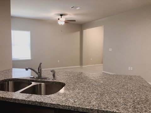A kitchen counter with a sink and a fan on the ceiling.